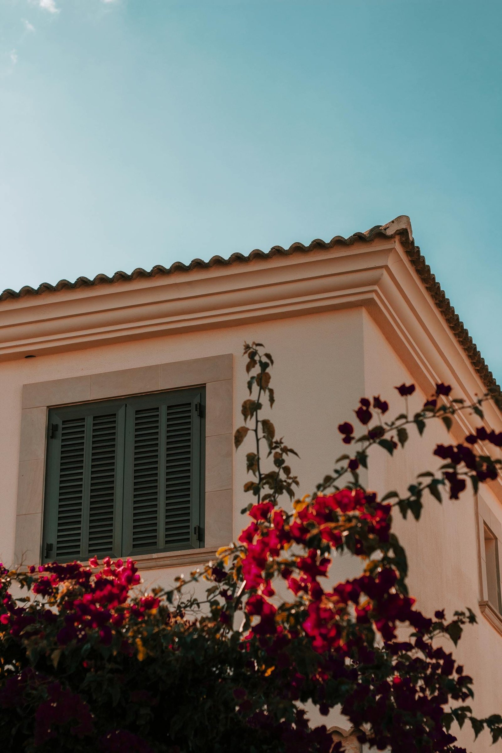 Charming Mediterranean villa facade with blooming bougainvillea under a clear blue sky in Mallorca, Spain.
