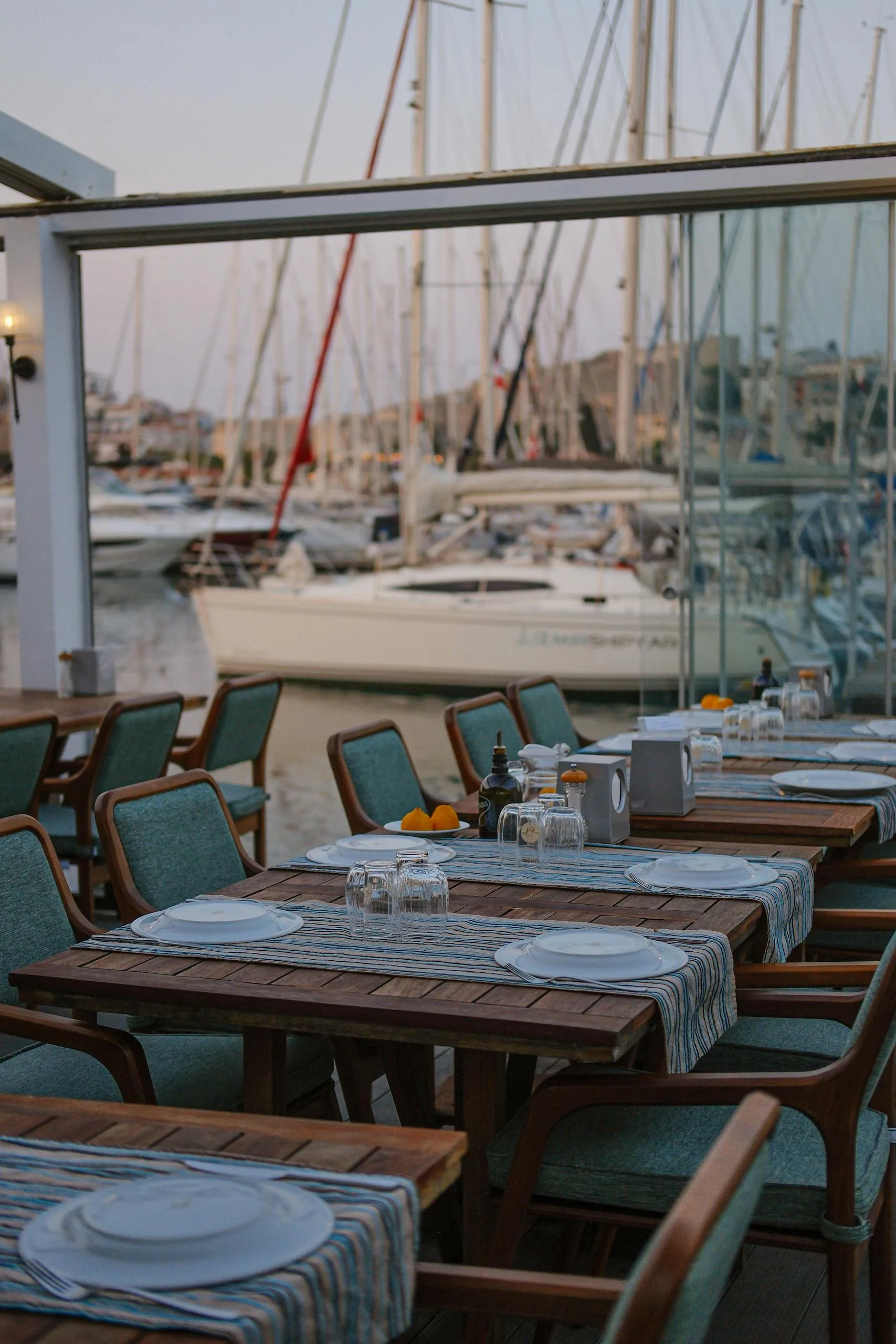 Charming outdoor cafe in İzmir overlooking a marina with yachts, perfect for relaxation.
